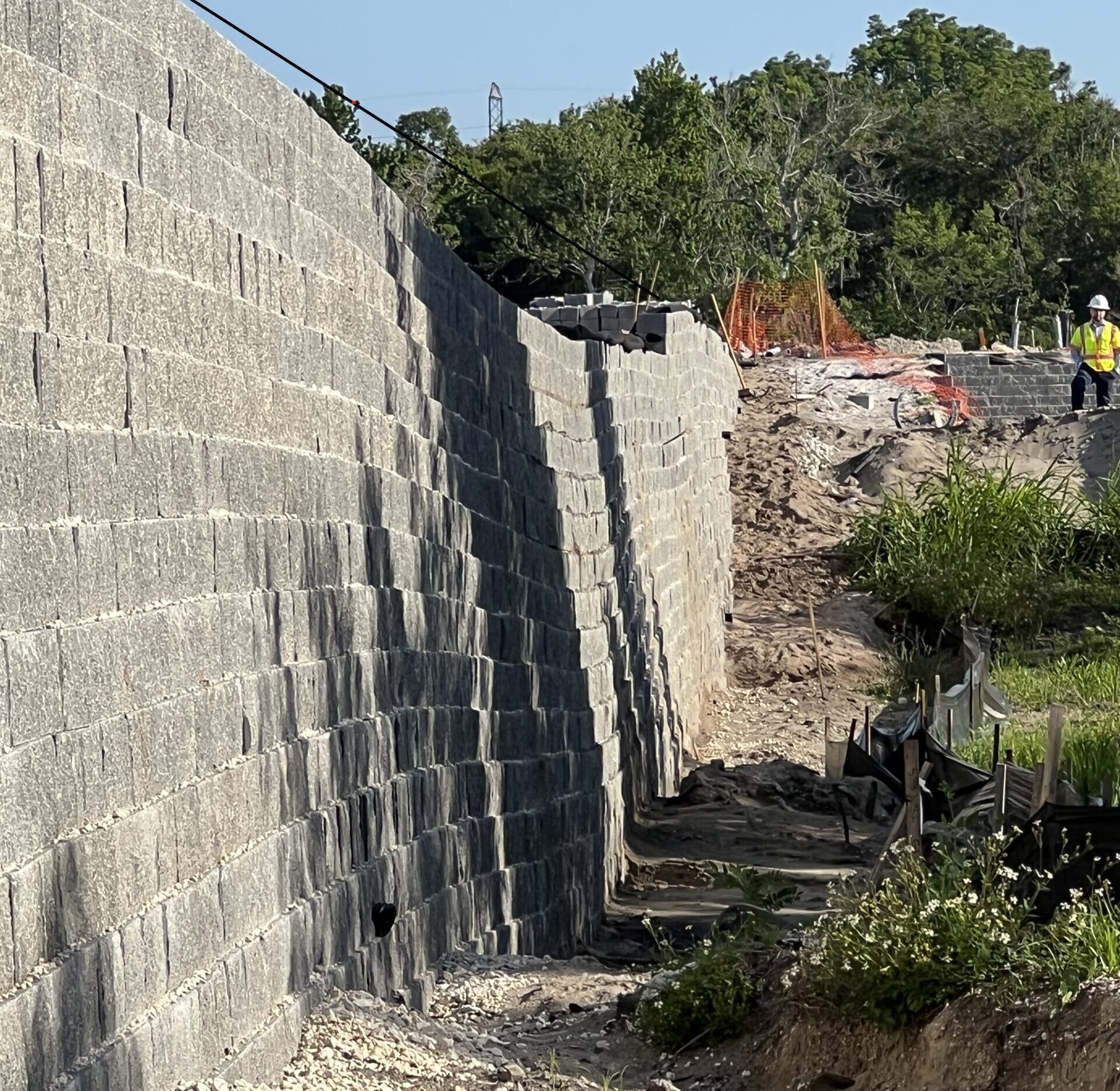 Photo of a retaining wall with a significant dip in the middle as a result of an underlying, previously undisclosed sinkhole affecting its integrity.